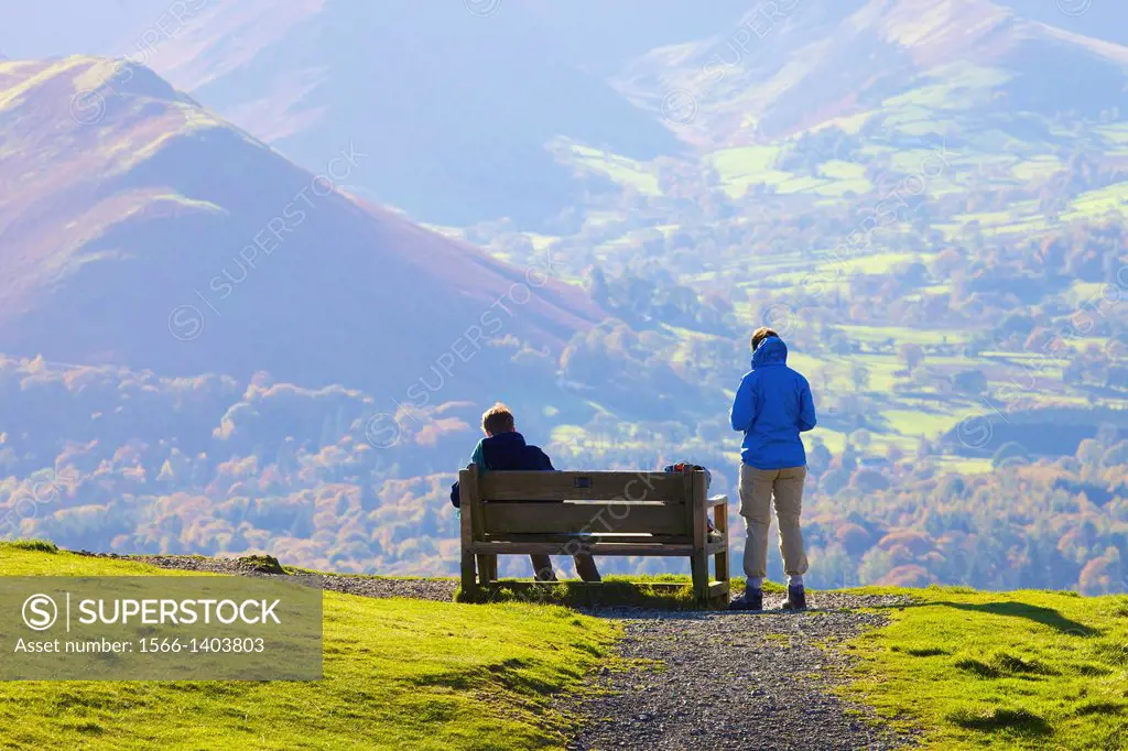 Tourists standing and sitting on a bench, enjoying the view of Cat Bells in the Lake District National Park Cumbria England United Kingdom Great Brita...