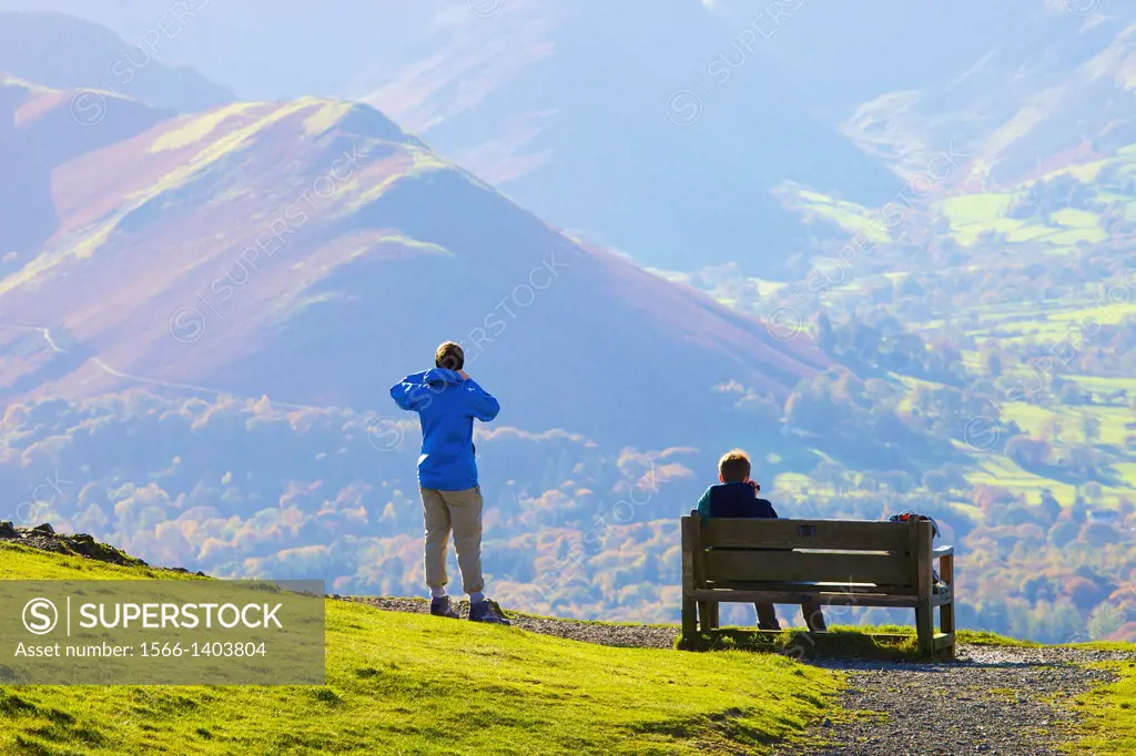 Tourists standing and sitting on a bench, enjoying the view of Cat Bells in the Lake District National Park Cumbria England United Kingdom Great Brita...