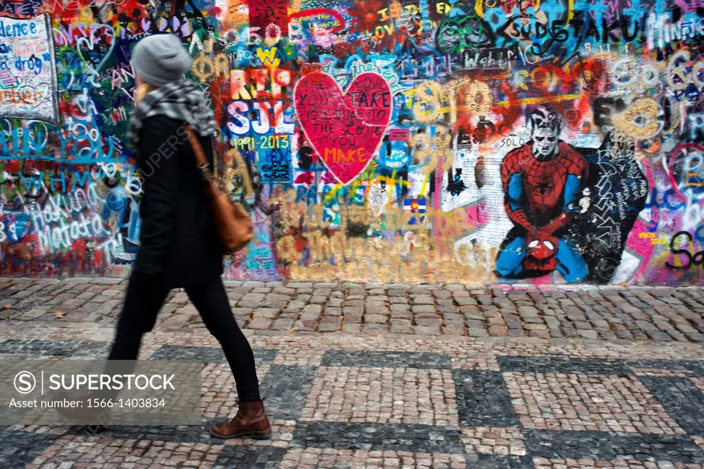 A girl walks past the John Lennon Wall in Prague center . The John Lennon Wall is a wall, which once was one most of which could be found in any of th...