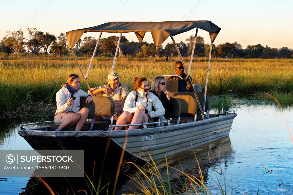 Tourists enjoying the last rays of sun on the water safari camp made ‹‹from Eagle Island Camp by Orient Express , outside the Moremi Game Reserve in...
