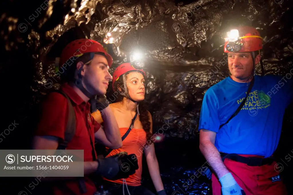 Tourists exploring the underground caves created by lava in the Grand Brûlé. Cooling and crystallization of basaltic lava around the sides, bottom and...