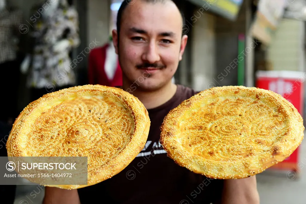 An Uighur man holding traditional Nan bread.