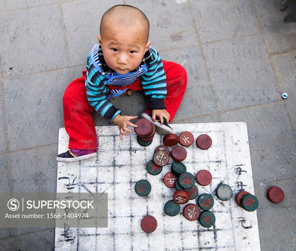 A cute Chinese boy playing Chinese chess.