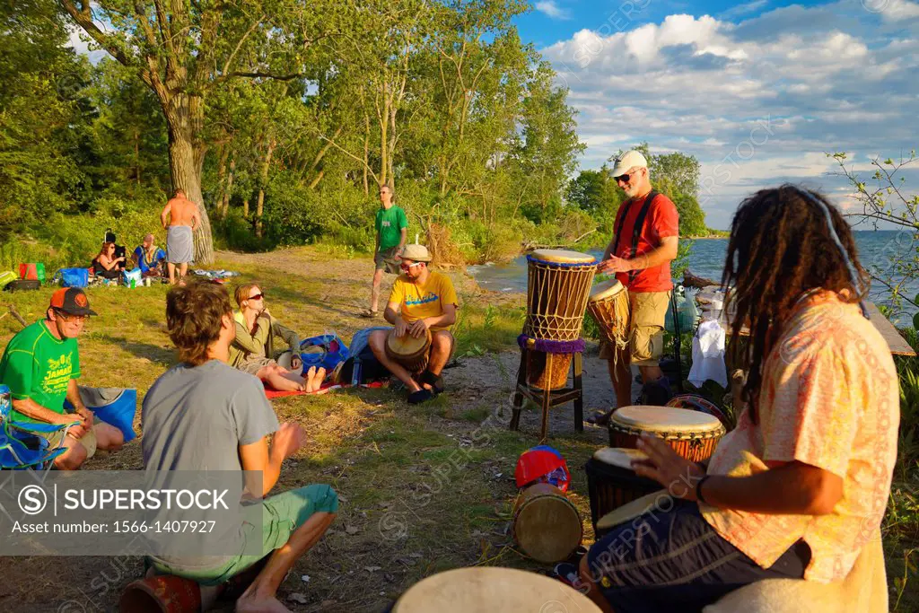 Group playing in a drum circle at Hanlan´s Point beach Toronto at sunset.