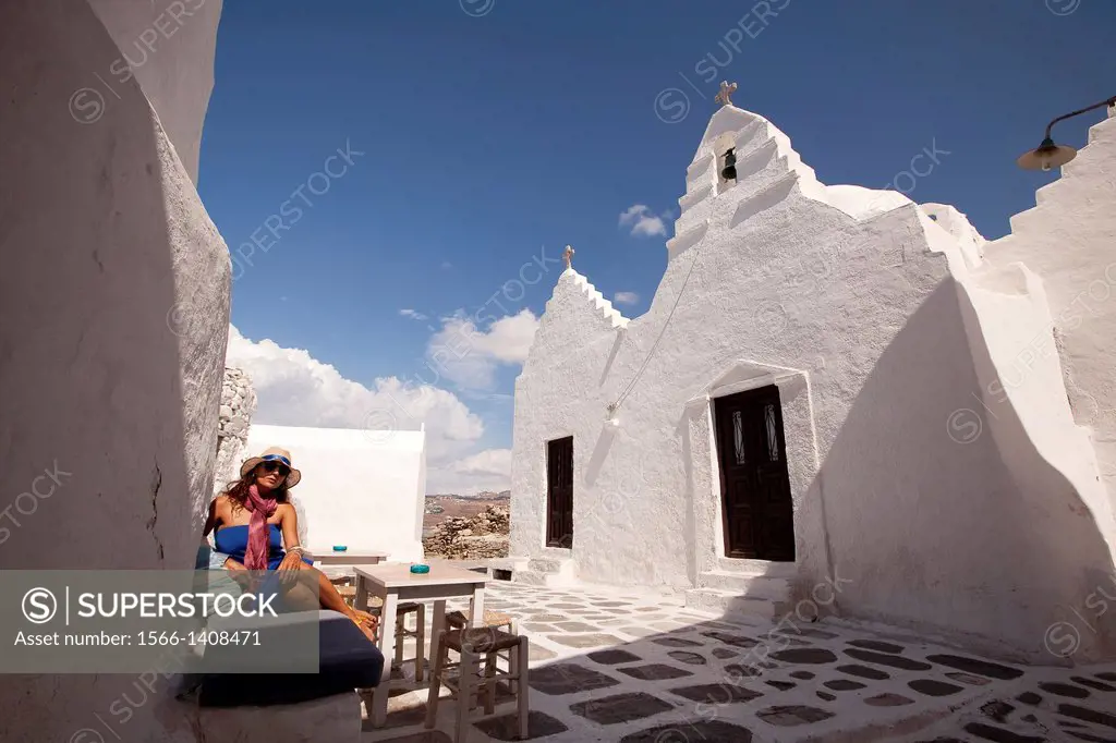 Woman sitting at a open-air cafe near Paraportiani Church, Mykonos, Cyclades Islands, Greek Islands, Greece, Europe.