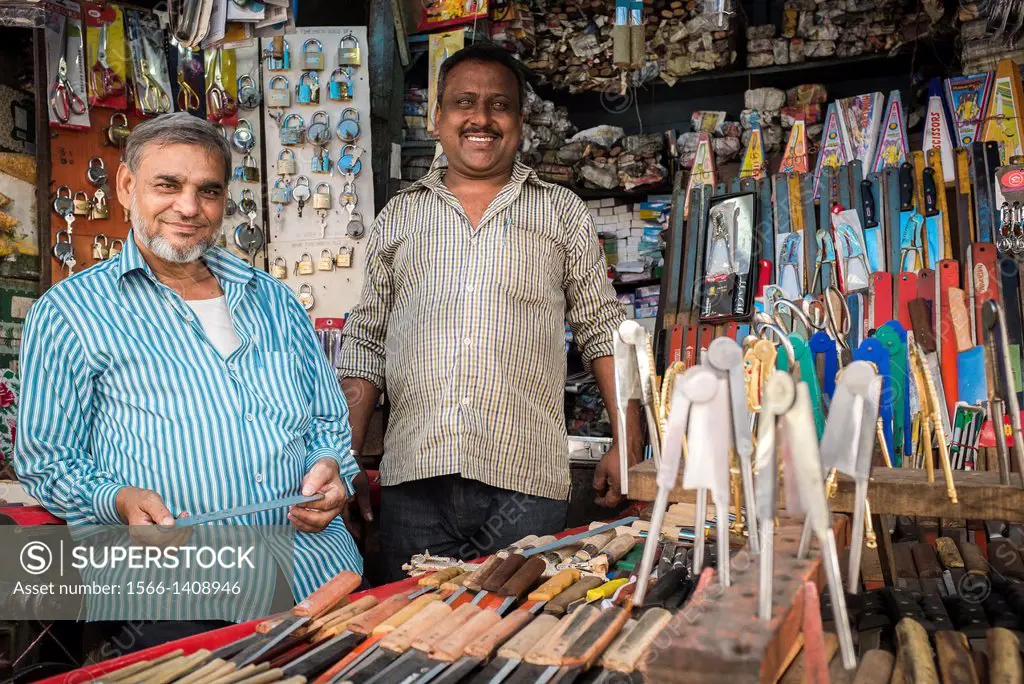 Two men in their shop specialising in metallic items including locks, knives and nutcrackers.