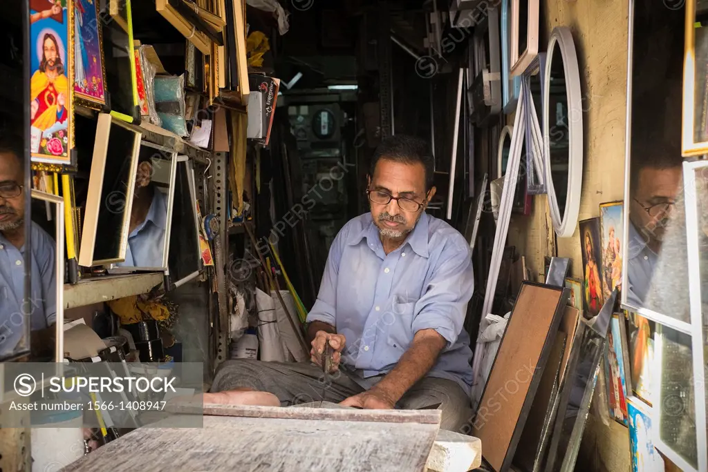 An artisan makes frames and mirrors in his small shop.