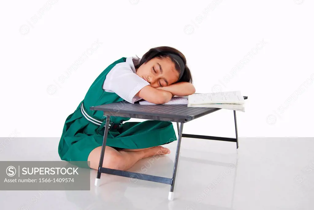 A schoolgril tired with studies fall asleep, Pune, India.