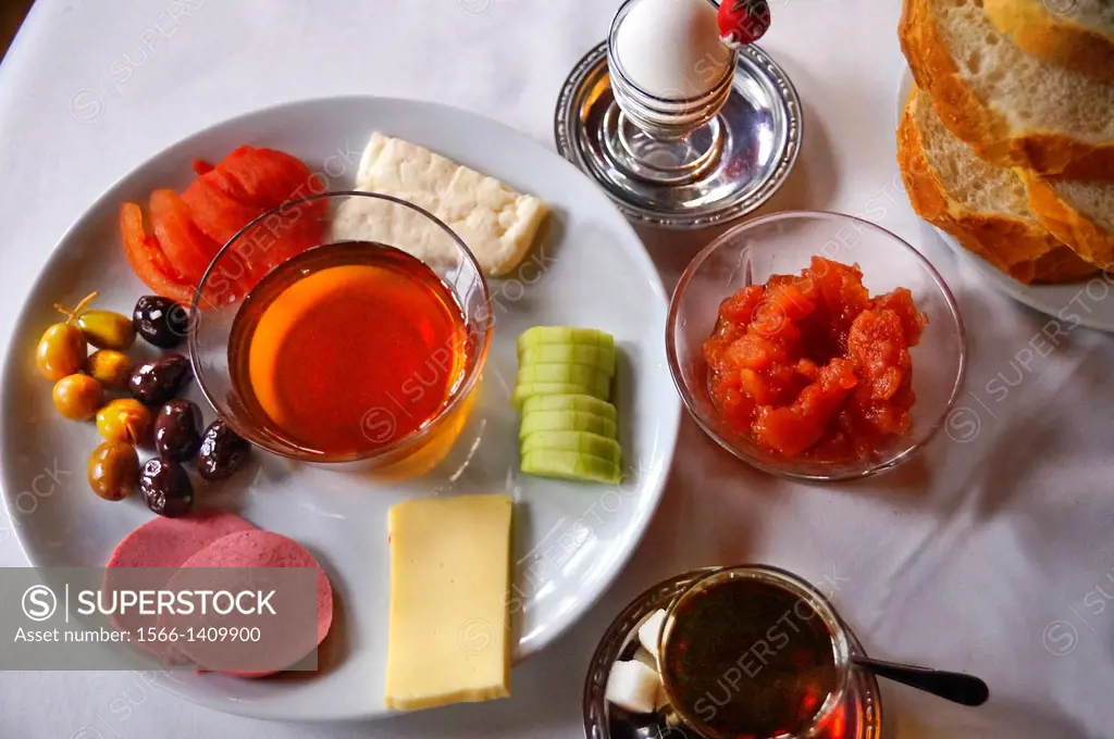 Typical Turkish breakfast with olives, tomatoes, sausages, honey, cheeses, cucumber, jam, egg, bread and tea, Turkey