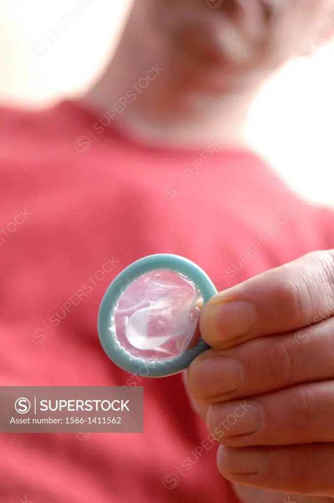 Sexual relationship. Man holding a rolled up condom.