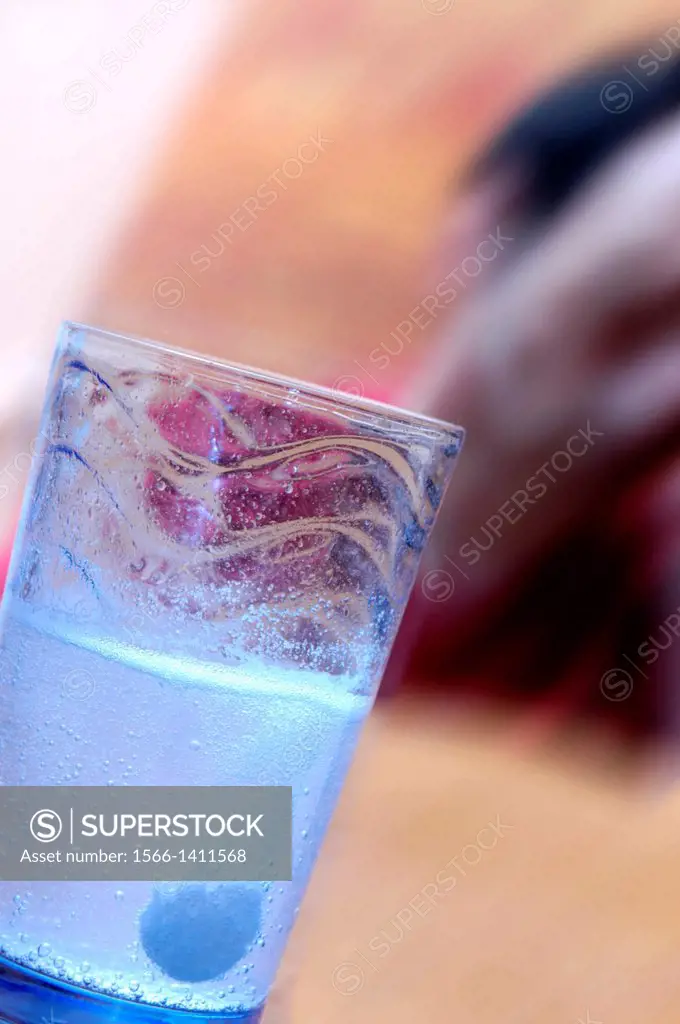 Soluble painkiller (analgesic) being put into a glass of water. The tablet will dissolve in the water, which is then drunk to relieve the pain from a ...