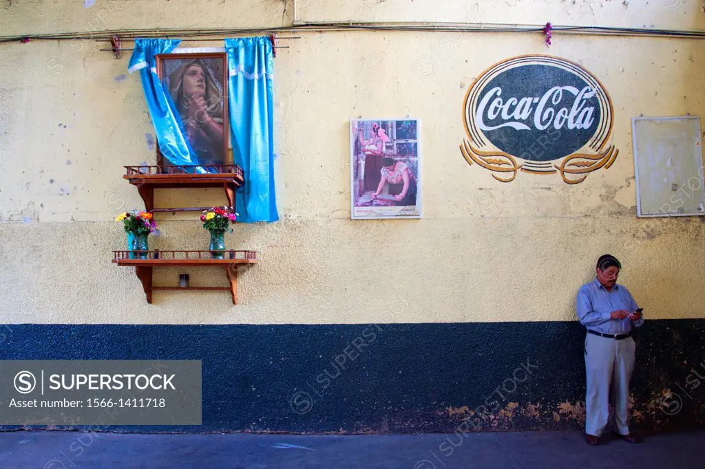 Man take a stop near Madonna and a vintage coca´s logo. Oaxaca, Oaxaca. Mexico