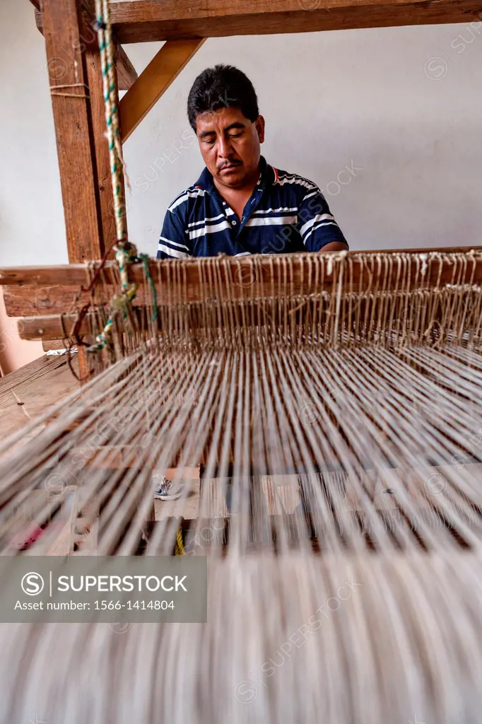 A Zapotec indigenous man uses a hand loom to weave traditional carpets October 30, 2013 in Teotitlan de Valle, Mexico.
