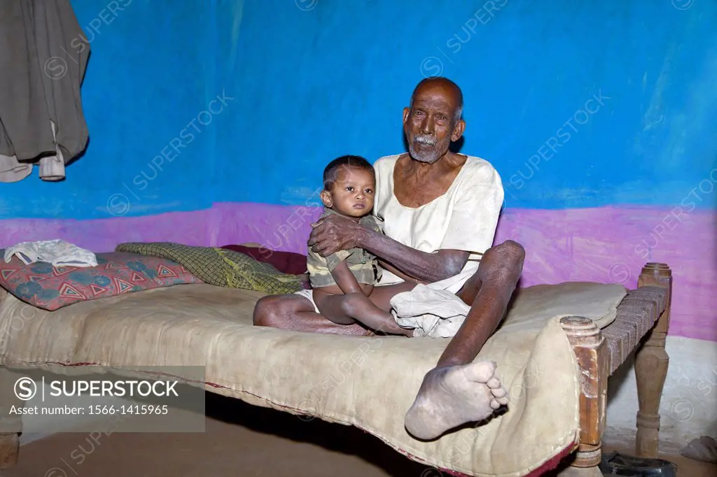 Grandfather and Grandson sitting on a cot. Khalwa, Madhya Pradesh, India.
