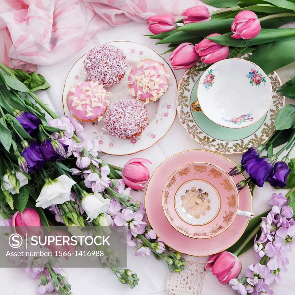 Antique china tea cups with cup cakes and floral bouquet Lissianthus, Tulips and Mathiola flowers, still life.