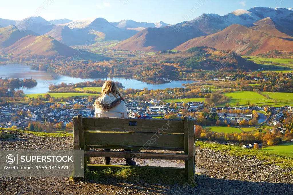 Female walkers sitting on a bench looking at the view above Derwentwater in the Lake District National Park with the Northern Fells in background.