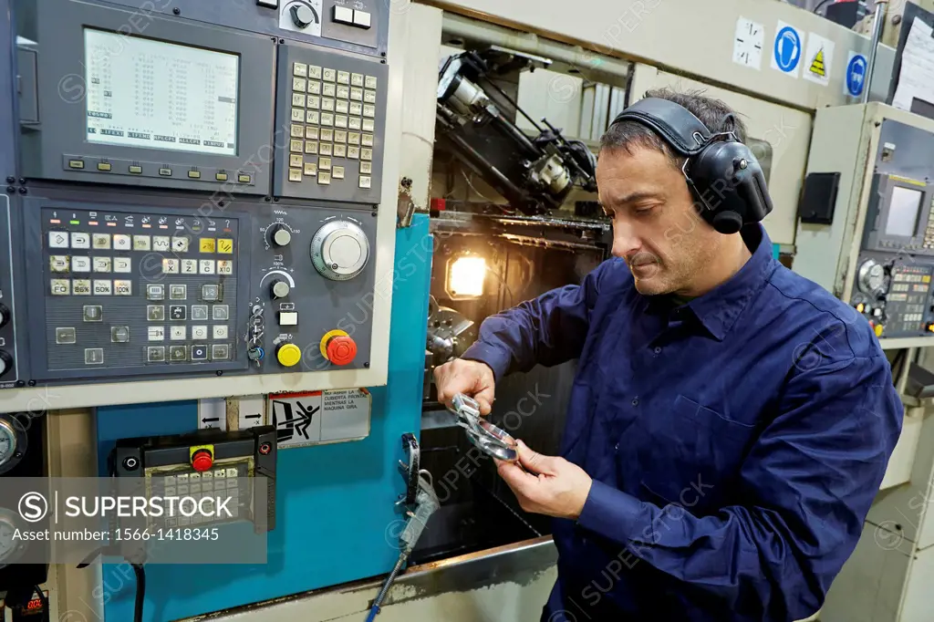 Worker measuring with caliper. Area automated CNC lathes. Machined Indecober. Machining of precision parts in series. Automotive industry. Berriz. Biz...