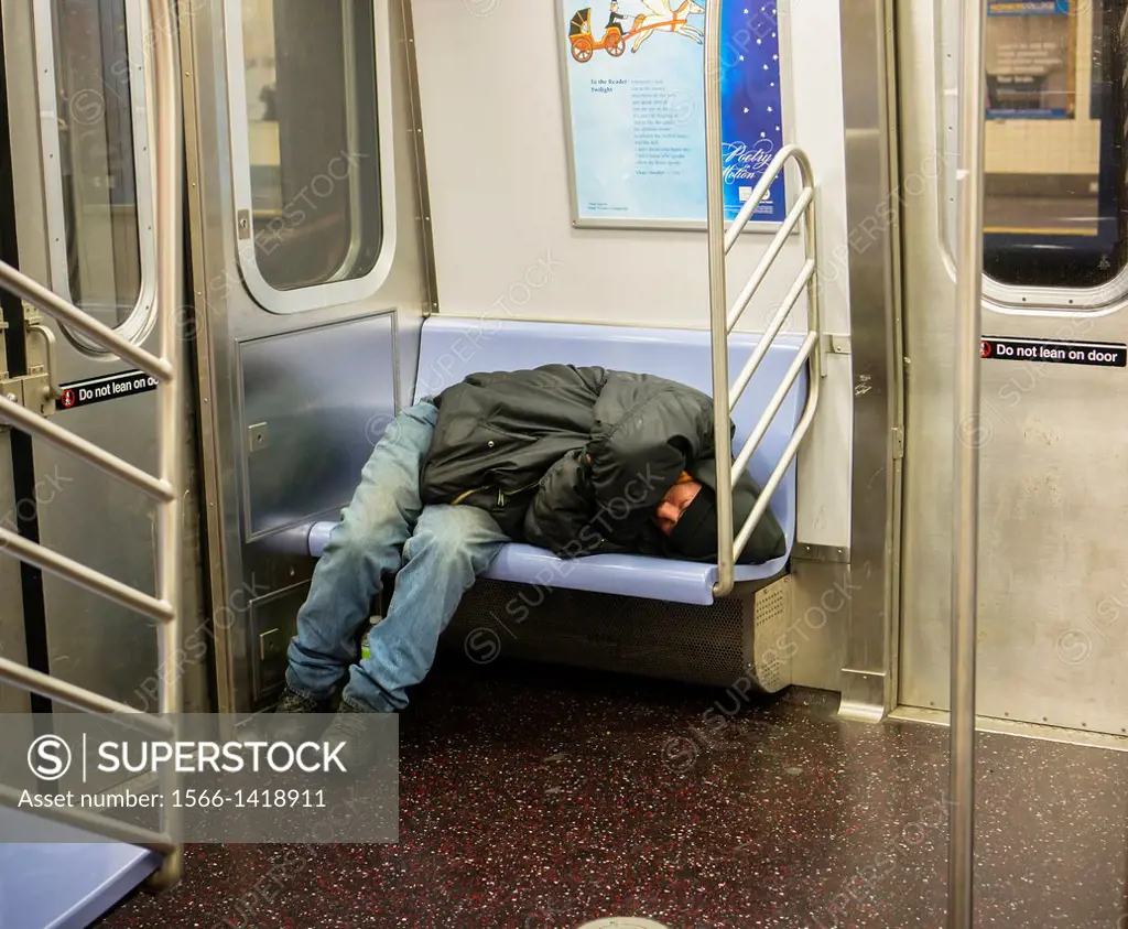 Homeless man takes up several seats as he sleeps in a subway car in New York