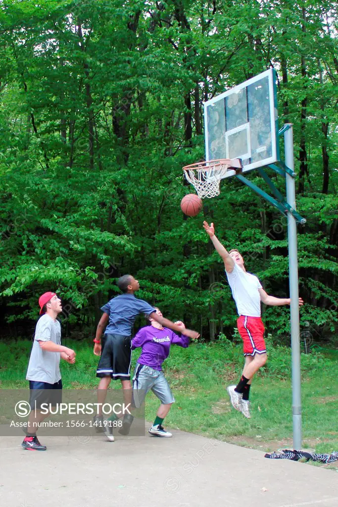 A player goes for a lay-up during a pick-up neighborhood basketball game as his opponents tries to block him.