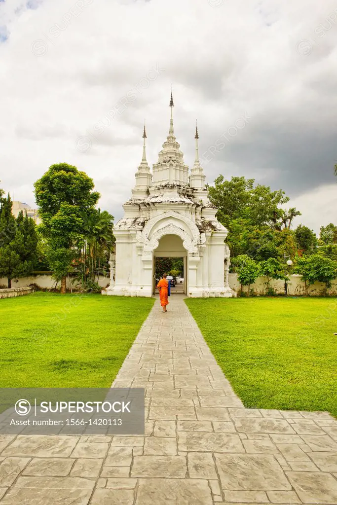 Monk walking through the entrance gate to Wat Suan Dok Temple, Chiang Mai, Thailand.