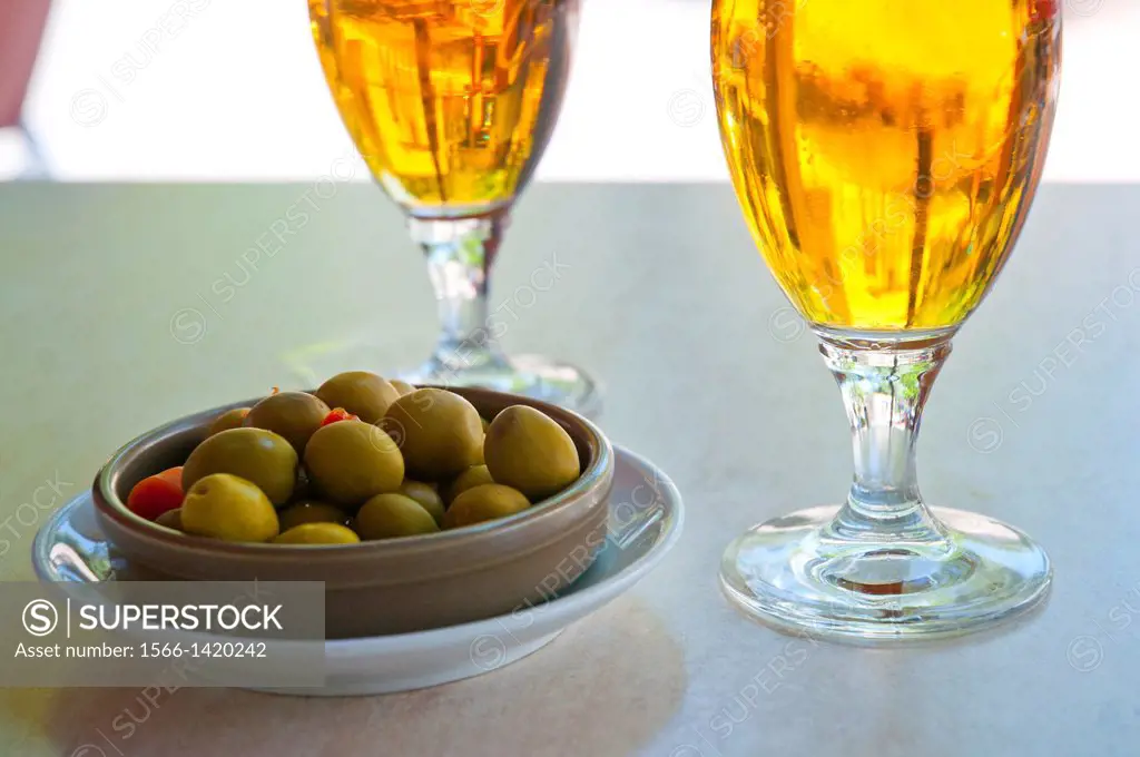 Spanish aperitif: two glasses of beer and green olives in a terrace. Spain.