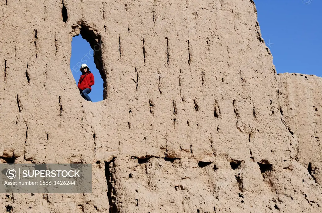 Woman in a hole in a wall of Qyzyl Qala desert fortress. Uzbekistan, Karakalpakstan. Model Released.
