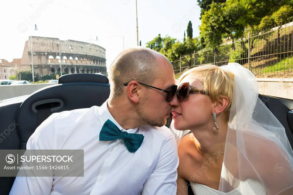 Newlyweds kissing at the Roman Coliseum. Rome, Italy.