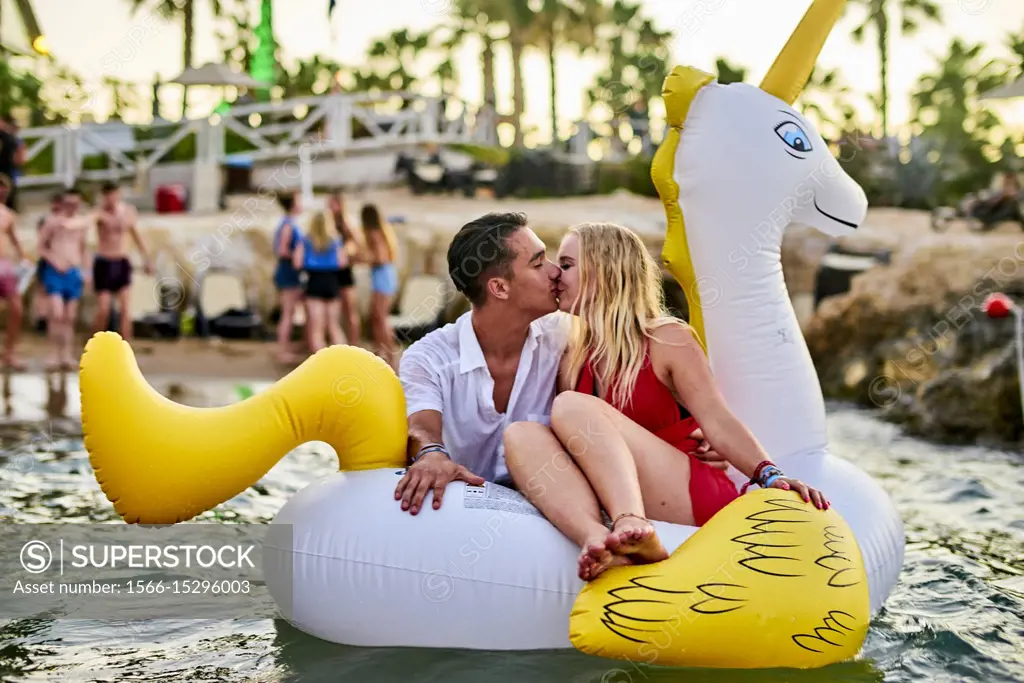 Greece, Crete, Chersonissos, couple at Beach Party sitting on inflatable, kissing, romantic