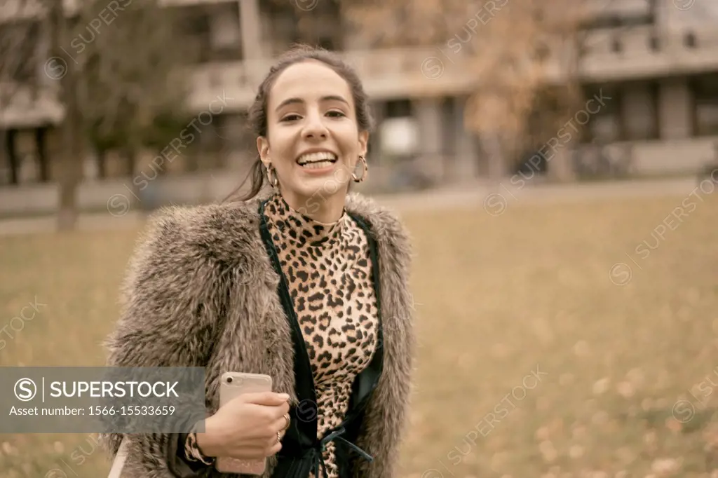 fashionable lively woman walking outdoors in park, autumn season, wearing coat, happiness, candid emotion, unposed walking in city, Munich, Germany.