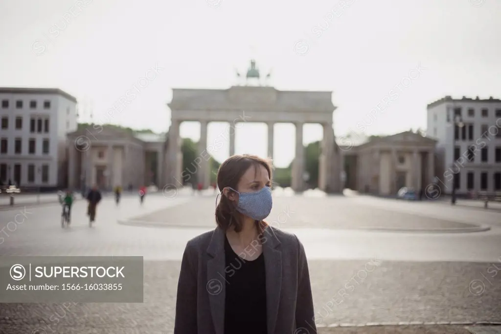 Woman with mask walking in Berlin in an empty Brandenburg gate.