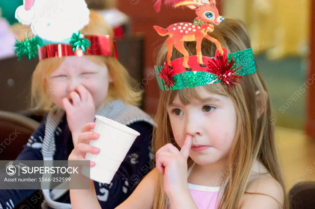 3 year old girl at a party picking her nose, with a girl in the background mimicking her