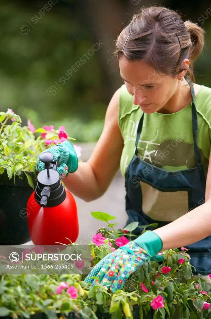 Woman spraying flowers in garden