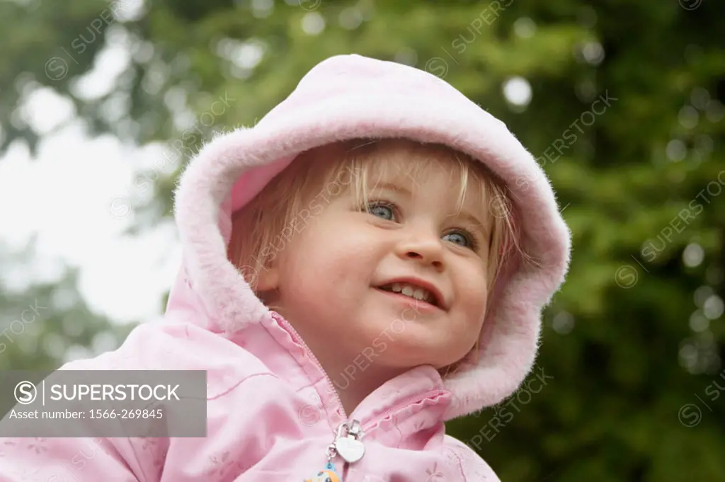 18 month old girl outside, with her hood up, smiling
