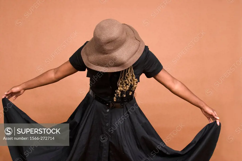 Young black woman, wearing a hat, holding up the corners of her dress