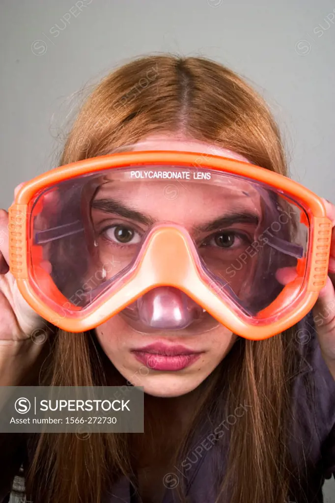 Young woman, with long red hair, looking through a pair of swimming goggles