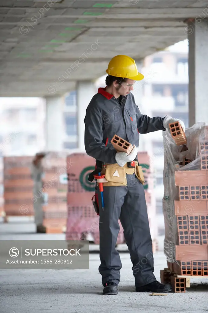 Worker picking bricks. Housing construction, apartments. San Sebastian, Gipuzkoa, Euskadi. Spain.