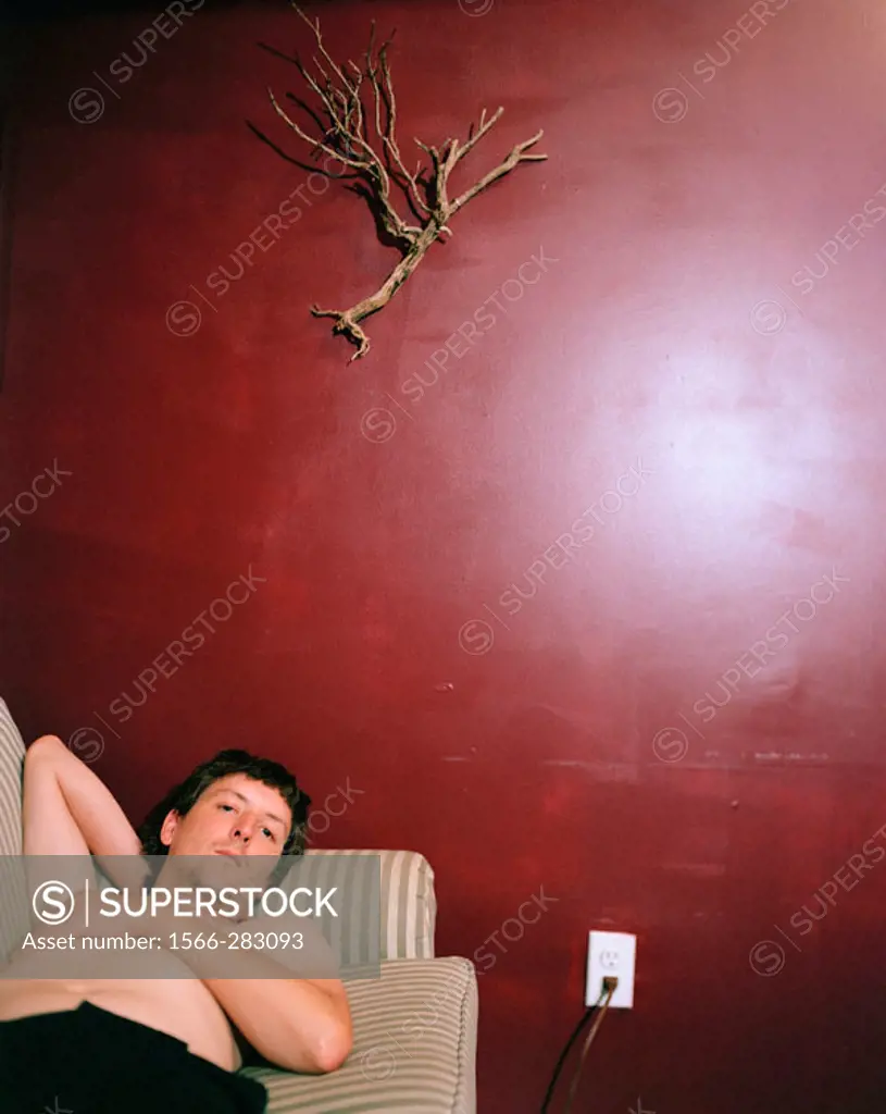 Man laying on couch against red wall.