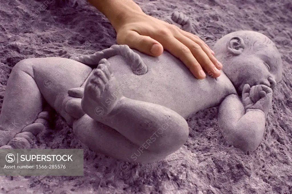 Hand touching a stone baby