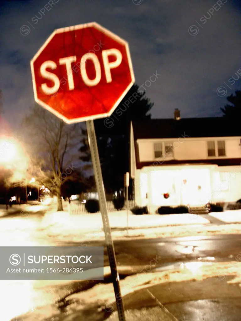 A bright red Stop Sign is captured at night on a surburban street with a slight blur creating a ghostly, painterly effect.