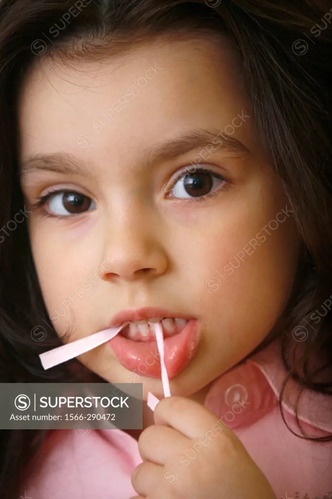 Minor girl portrait grimacing and with chewed plastic straw in her mouth