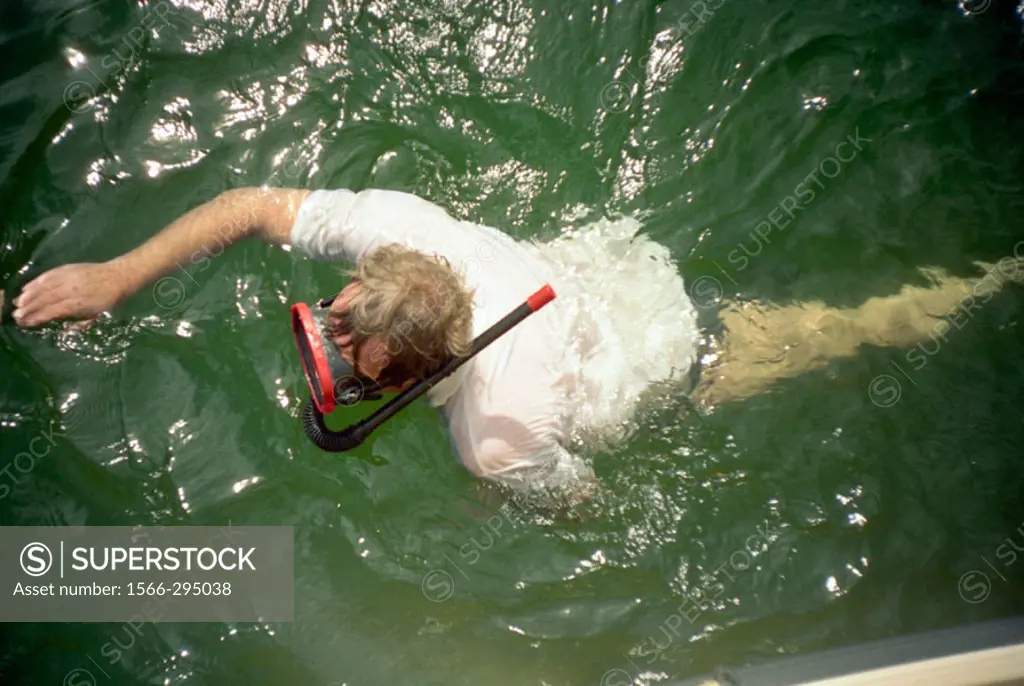 Man swimming with snorkel and mask. Slite harbor on the island of Gotland, Sweden.