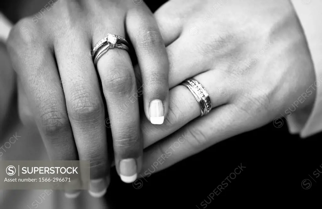 Bride and groom with wedding bands and hands crossed