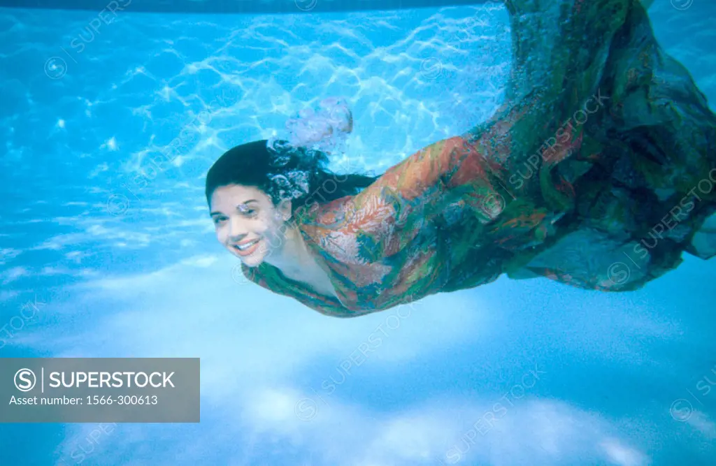 Woman in dress swimming underwater
