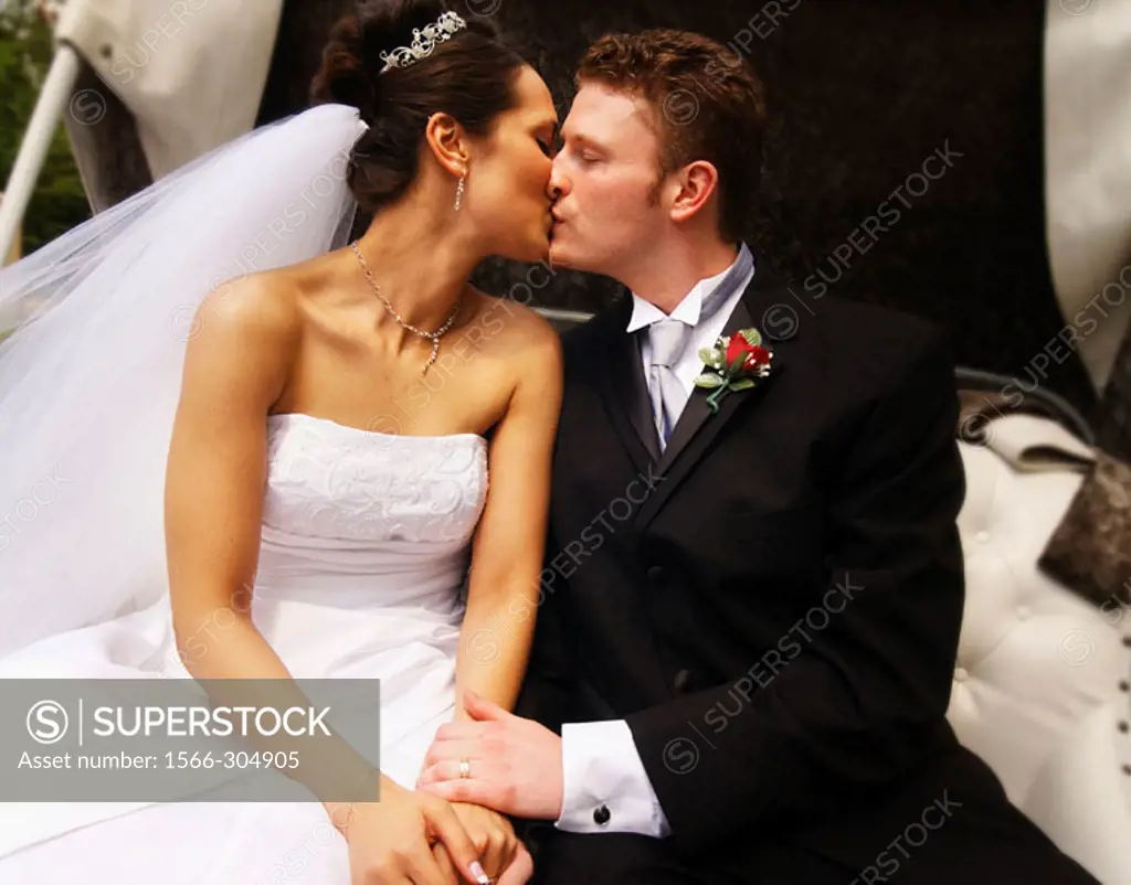 Bride and groom kissing in carriage