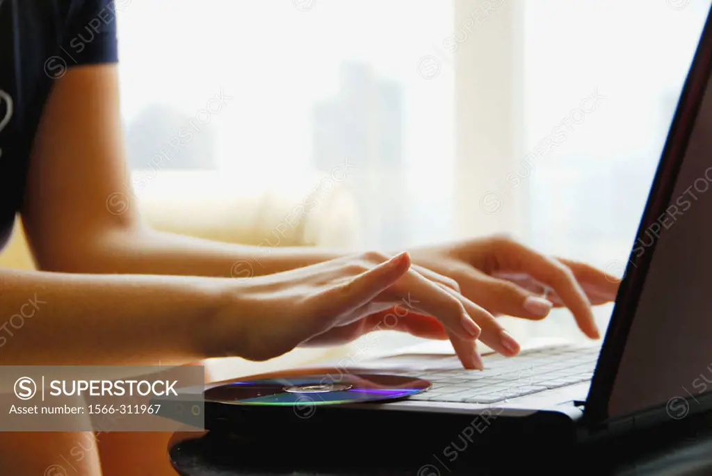 20 yr old woman typing on laptop computer at home