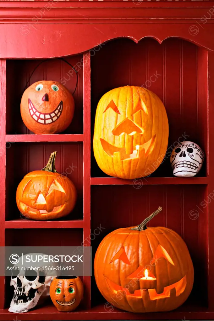 An old red cabinet with Halloween items, carved pumpkins, skulls