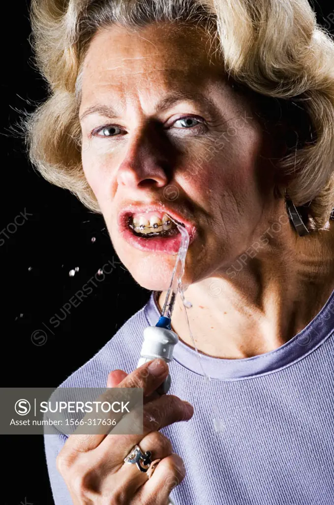 Woman cleaning braces with a water pik