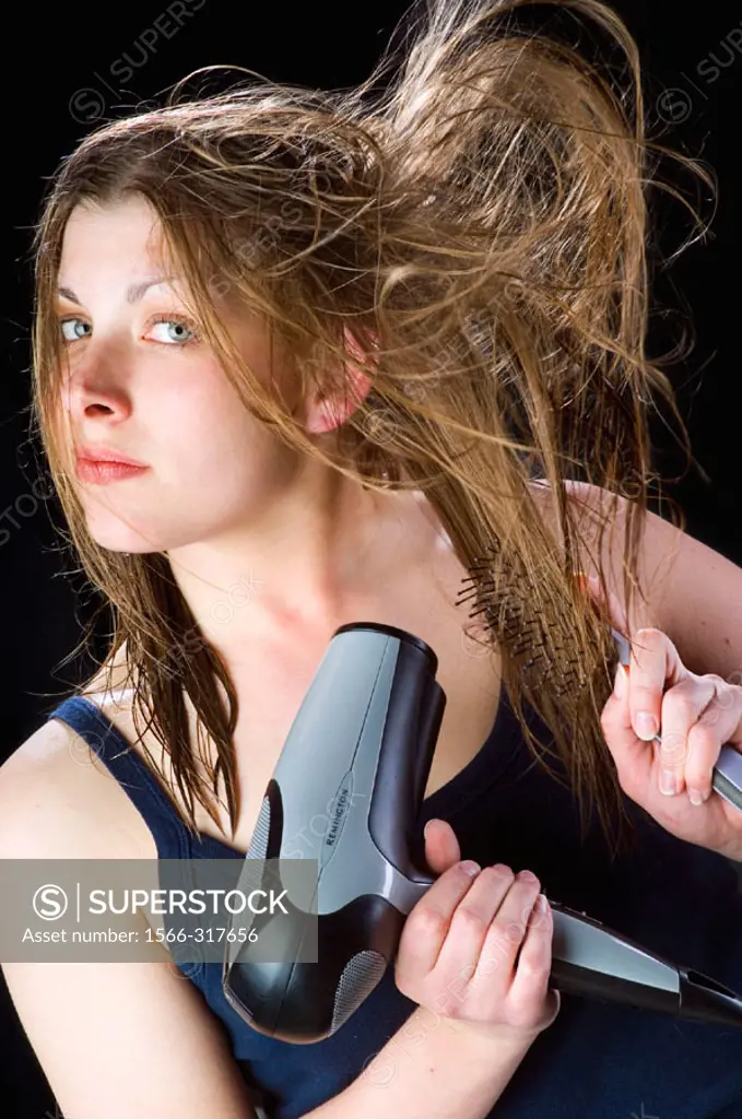 Young woman blow drying her hair