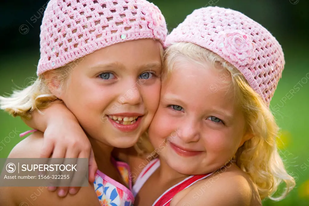 Caucasian blonde sisters hugging and smiling