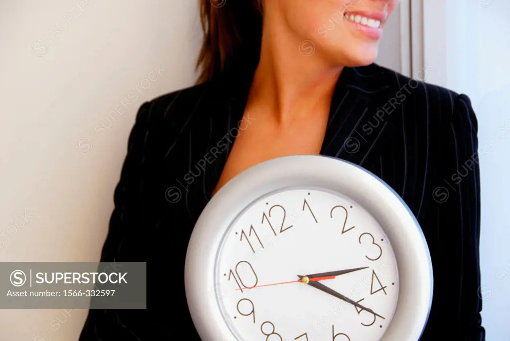 20 yr old young woman holding clock in office